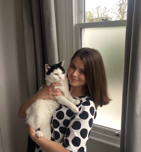 Ana holding her black and white cat while wearing a black and white shirt.