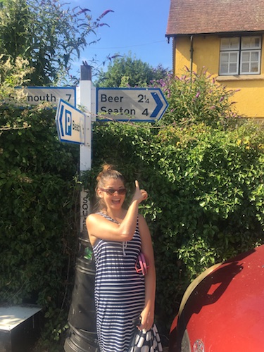 Ana pointing at a road sign that shows a place called Beer two miles away.